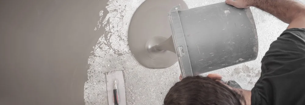 Person gießt Estrich mit Eimer